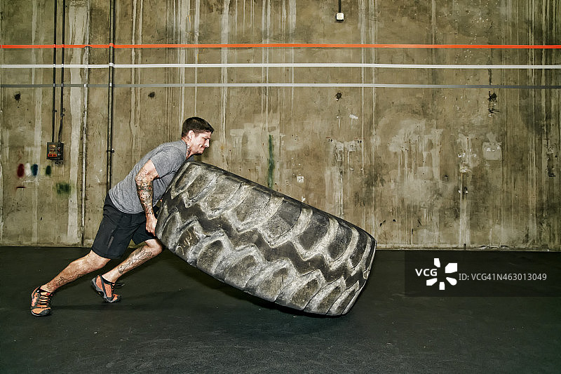 在健身房举起大轮胎的白人男子图片素材