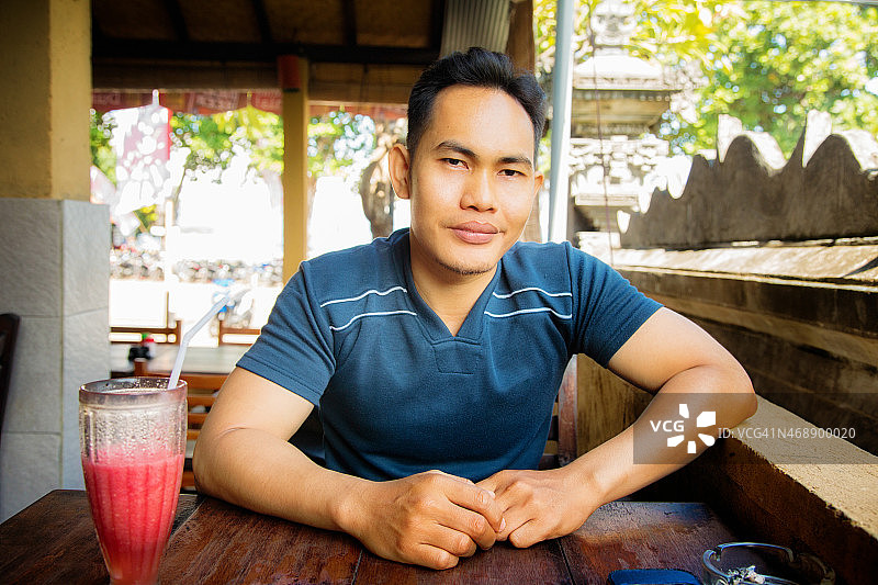 在巴厘岛咖啡馆里放松的中年印度尼西亚男人图片素材