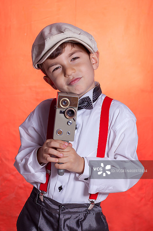 男孩身穿燕尾服，用复古相机拍照图片素材