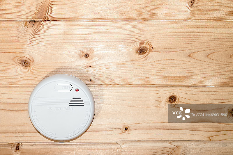 安装在木制天花板上的白色家用烟雾探测器图片素材