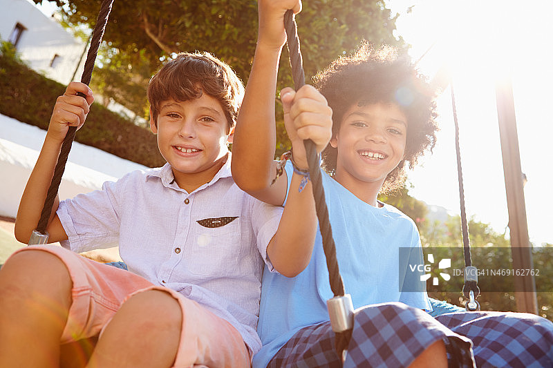 游乐场荡秋千的两个女孩和男孩图片素材