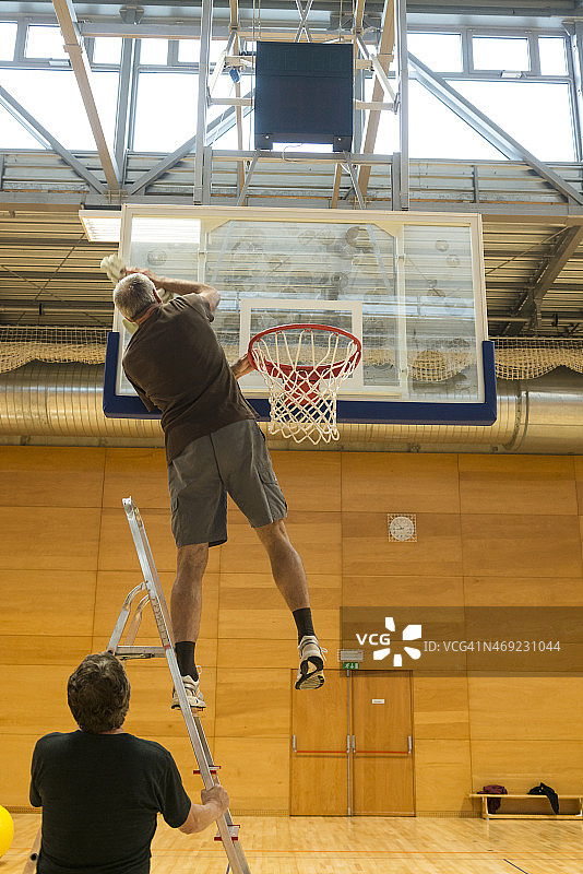两位年长的男人在学校体育馆清洁篮球板，欧洲图片素材