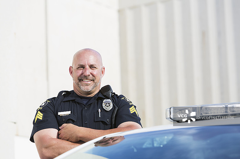 快乐的警官站在巡洋舰旁图片素材