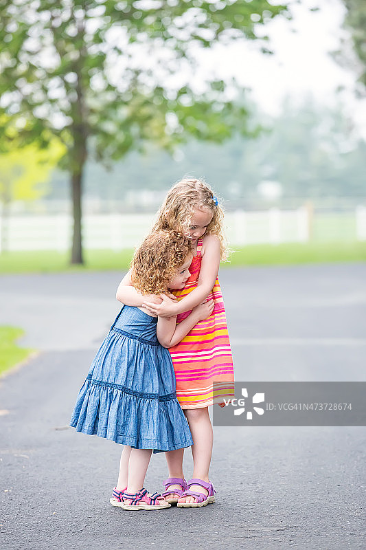 两个小女孩在春日户外拥抱图片素材