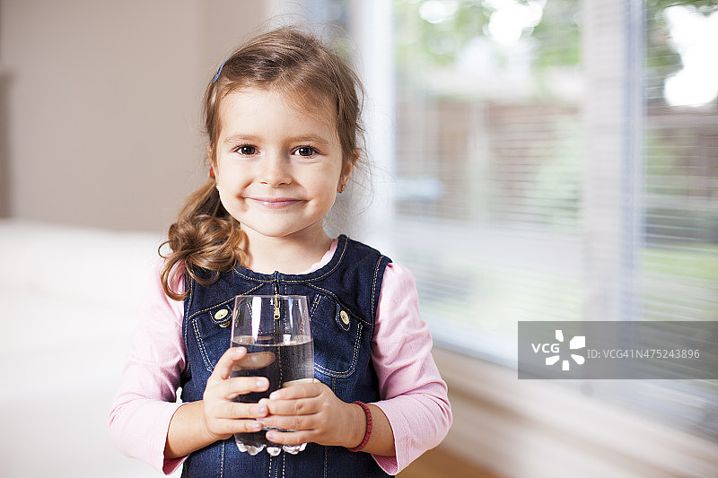 小女孩拿着水杯，看着镜头图片素材