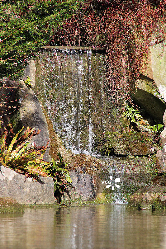 流水落入池塘岩石花园的景象图片素材