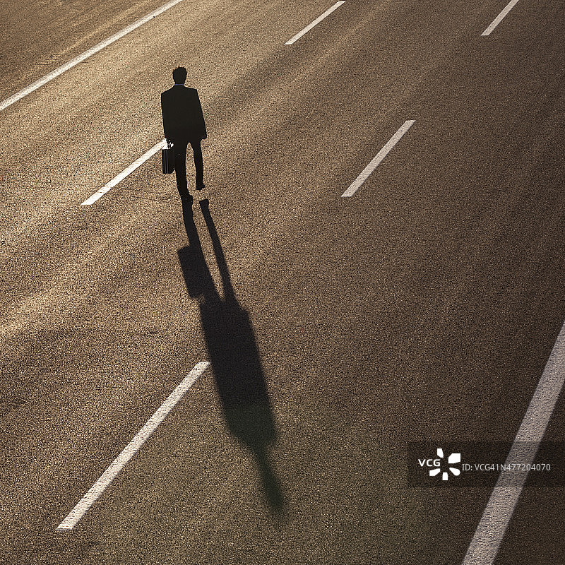 在高速公路中间行走的商人的剪影图片素材