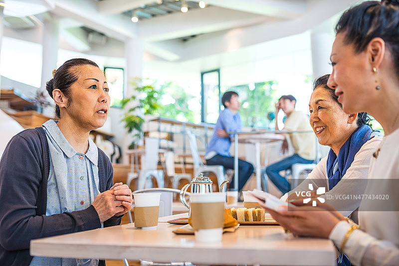 在咖啡馆里的快乐的日本老年妇女图片素材