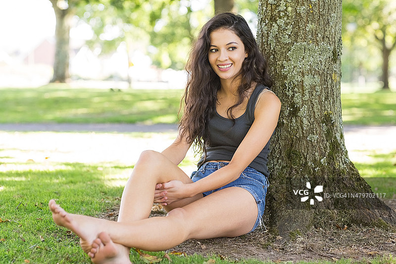 休闲快乐的棕发女人靠在树上图片素材