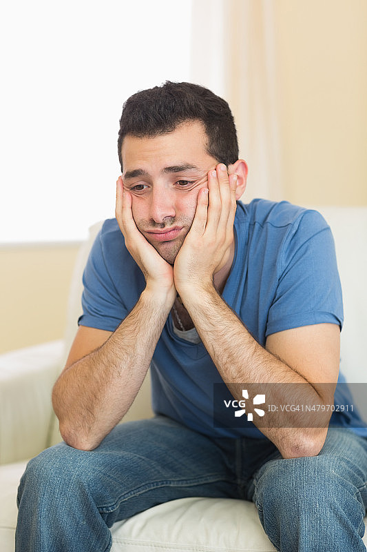 坐在沙发上的休闲悲伤男人图片素材