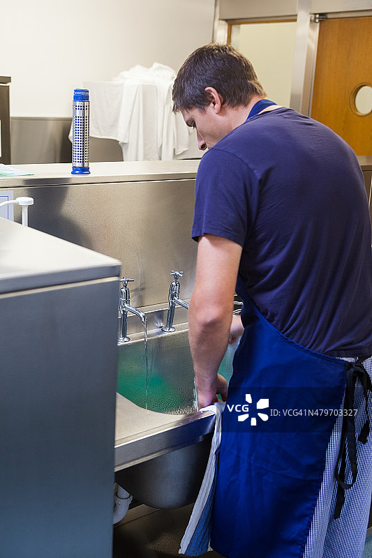 站在水槽后的厨房服务员图片素材