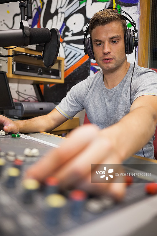 英俊且专注的电台主持人正在调节音量图片素材