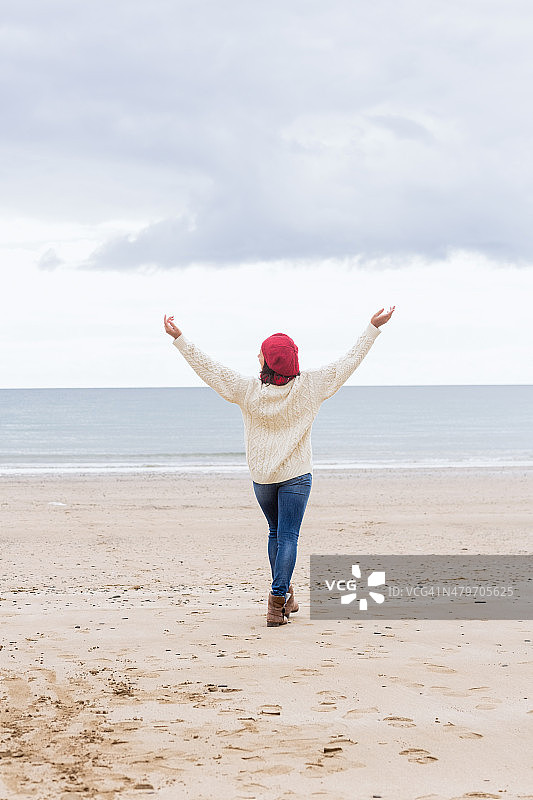 穿着休闲保暖服装的女人在海滩上伸展手臂图片素材