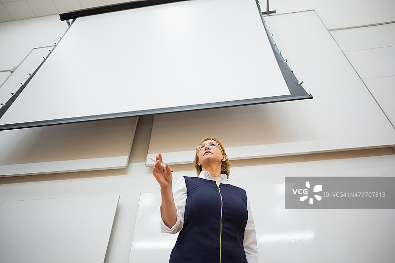 讲座大厅里使用投影屏幕的优雅教师图片素材