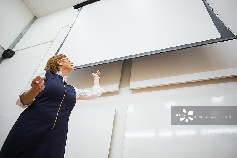 女教师在礼堂里使用投影屏幕图片素材