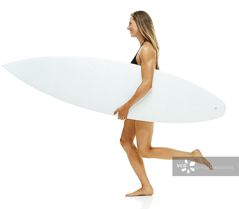 拿着冲浪板奔跑的微笑女冲浪者图片素材