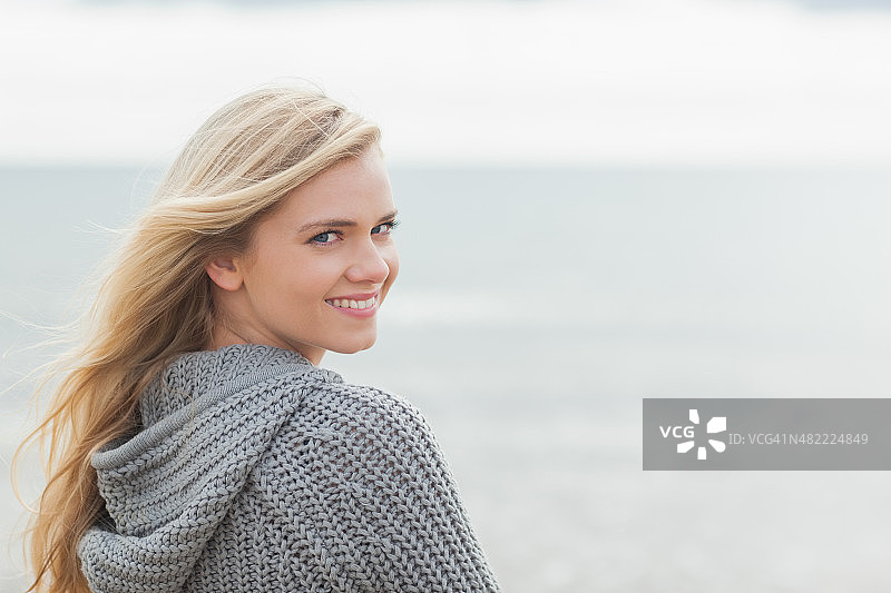 在海滩上穿着灰色针织外套的年轻女子图片素材