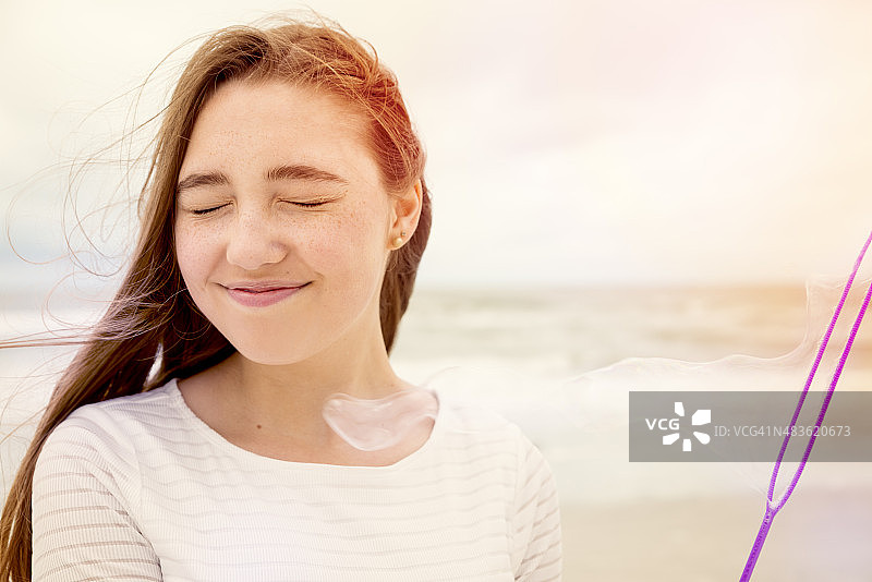 可爱的女孩在海滩上吹肥皂泡图片素材