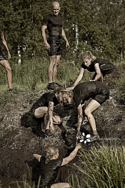 一群女人帮助朋友摆脱泥潭图片素材