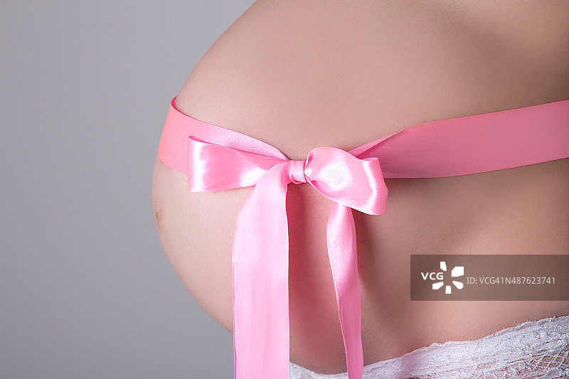 孕妇腹部系粉色丝带的特写图片素材