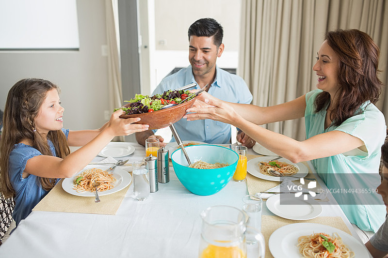 幸福的三口之家坐在餐桌旁图片素材