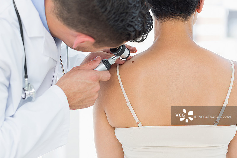 皮肤科医生检查女性背部的痣图片素材