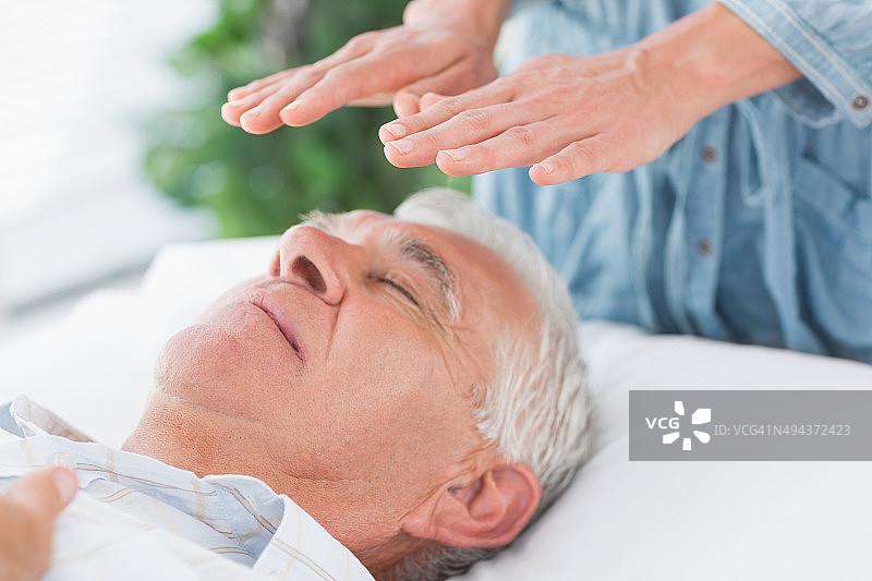 理疗师为老年男性进行灵气疗法图片素材