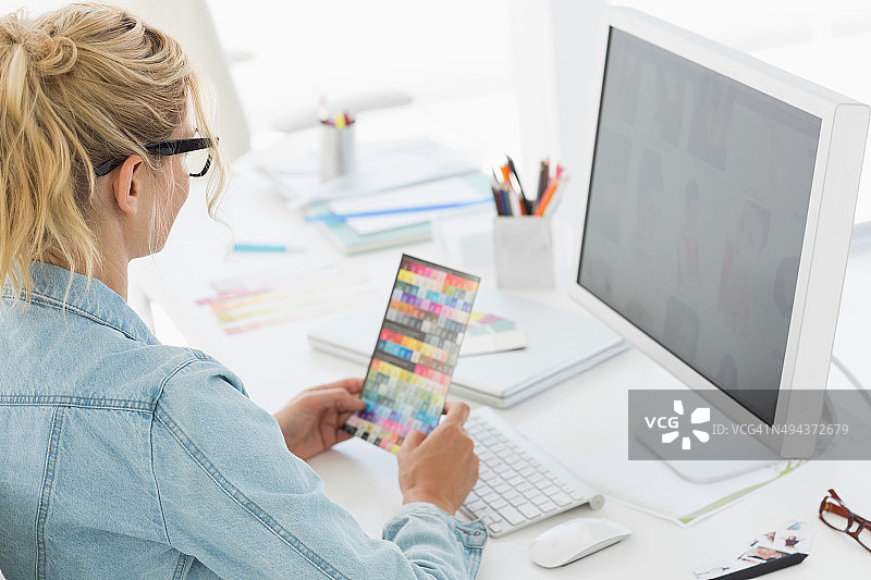 在办公桌前拿着色卡的金发设计师图片素材