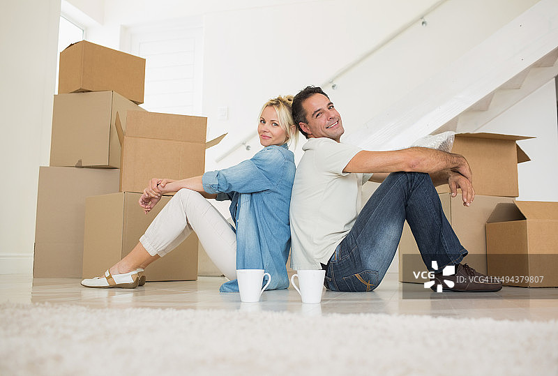 在新房里拿着杯子和盒子的微笑情侣图片素材