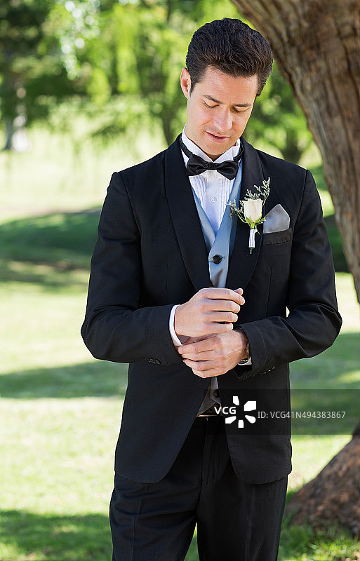 在花园里整理袖子的英俊新郎图片素材