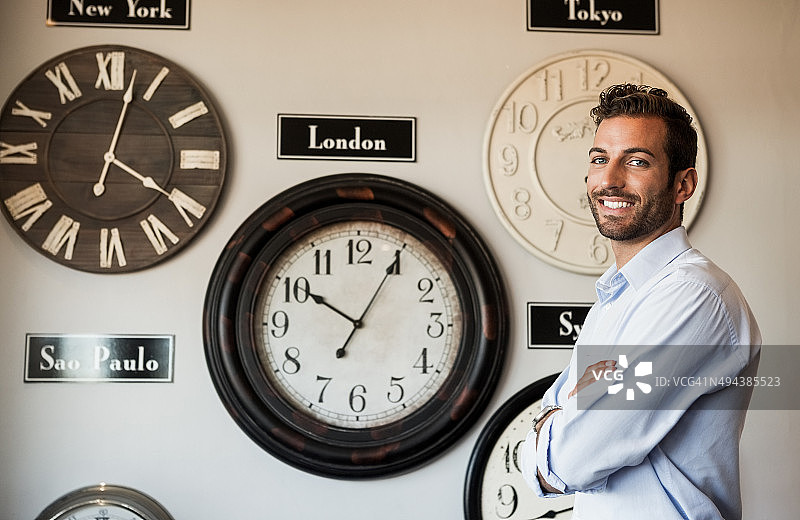 快乐的商人站在国际时钟墙边图片素材