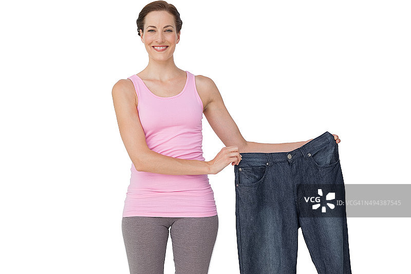 手拿旧牛仔裤的美丽健康女性肖像图片素材