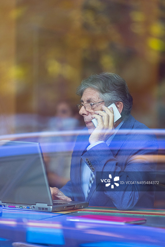 在咖啡馆使用手机和笔记本电脑的商人图片素材