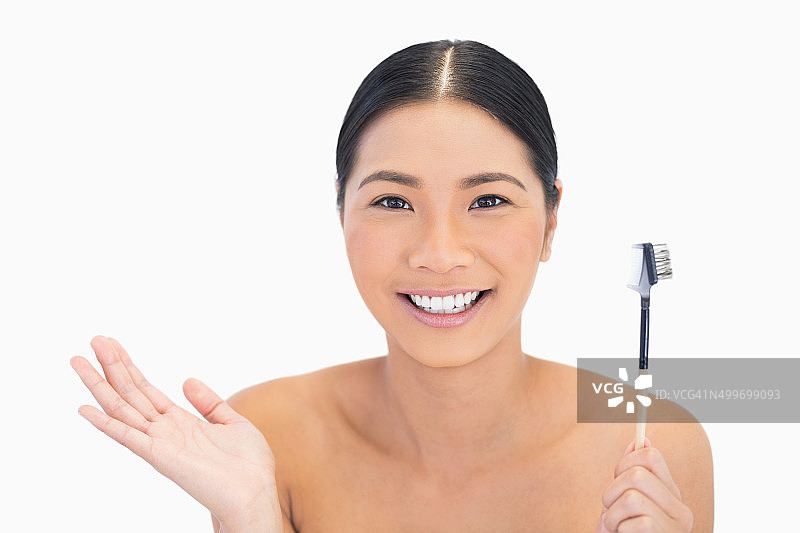 惊讶的自然黑发女子拿着眉刷图片素材