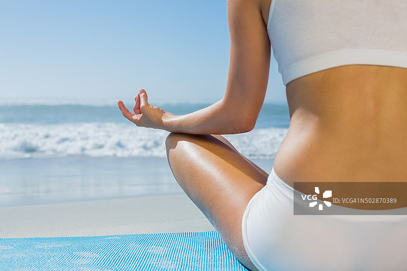 在沙滩上以莲花姿势坐着的健康女人图片素材