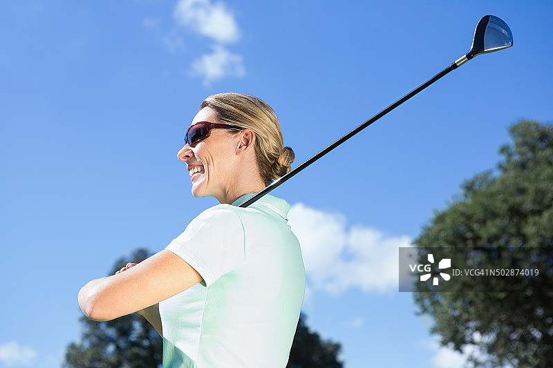 手持球杆微笑的女高尔夫球手图片素材