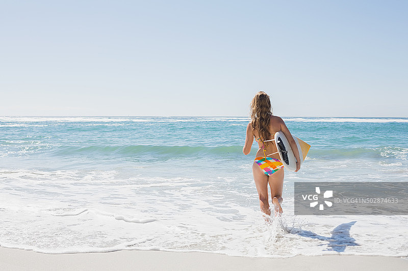 冲浪女孩抱着冲浪板走向大海图片素材