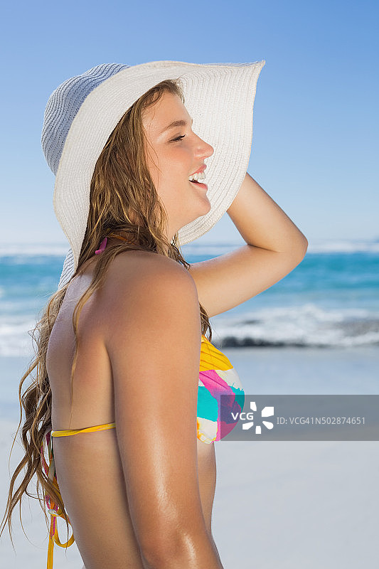 海滩上戴着比基尼和草帽微笑的漂亮女孩图片素材