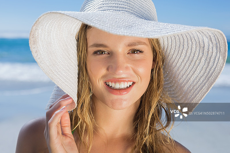 在海滩上对着镜头微笑的草帽美女图片素材