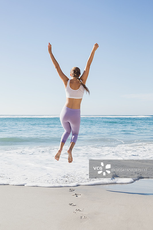 在海滩上跳跃的运动金发女郎图片素材