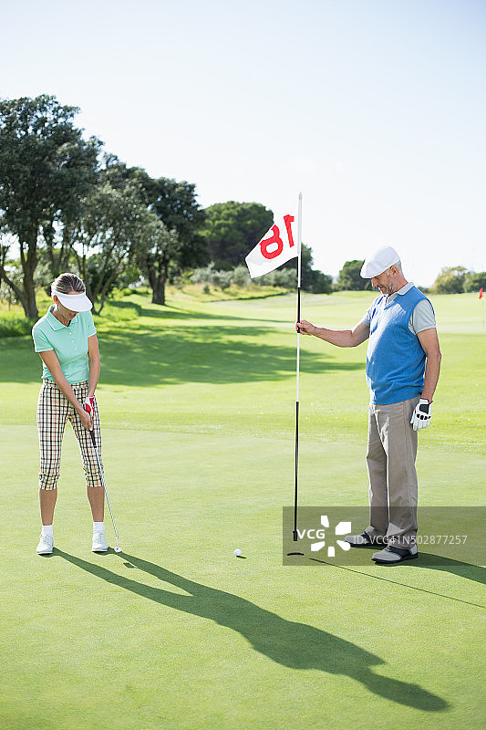 在高尔夫球场第十八洞的高尔夫情侣图片素材