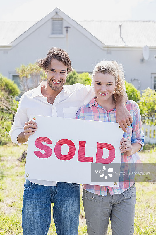 幸福的夫妇对着镜头微笑，手持已售标志图片素材