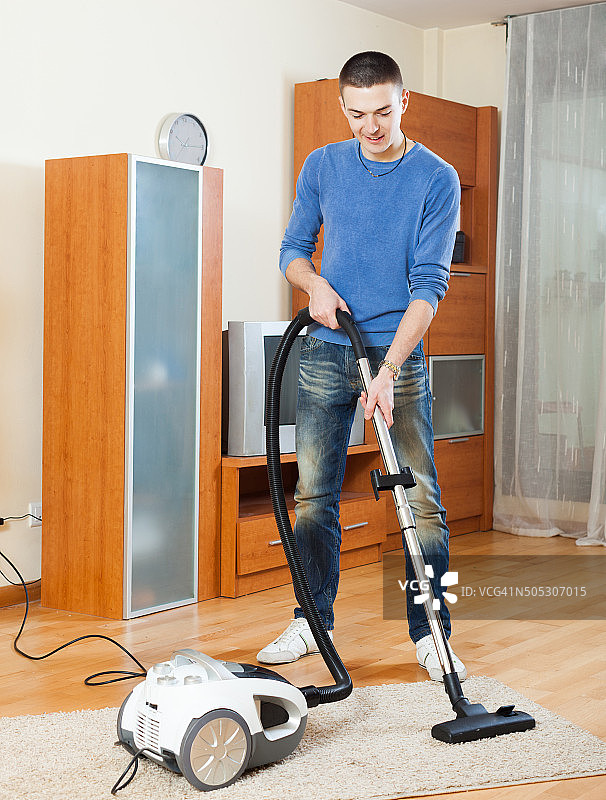 在客厅使用吸尘器的男人图片素材