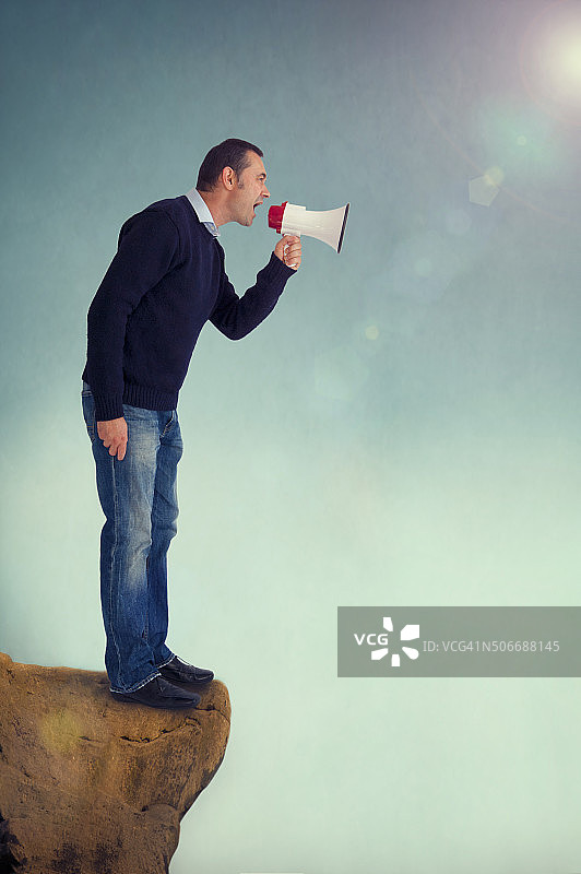 男人在悬崖边用扩音器喊话图片素材