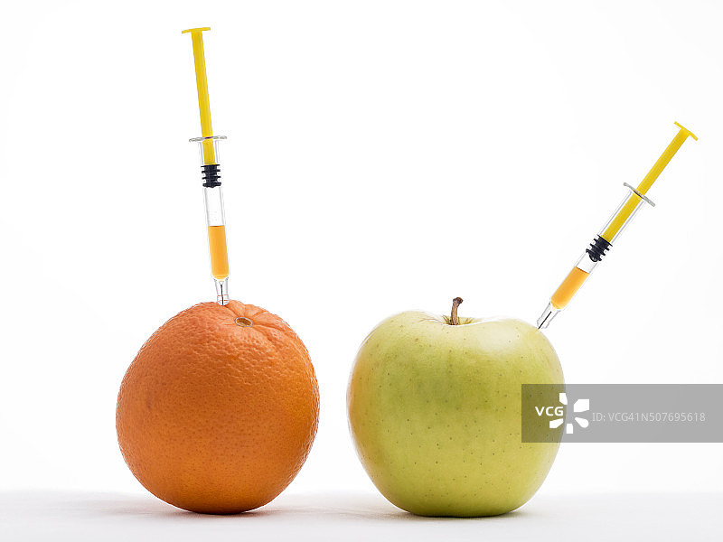 转基因食品概念：苹果和橙子上插着注射器图片素材