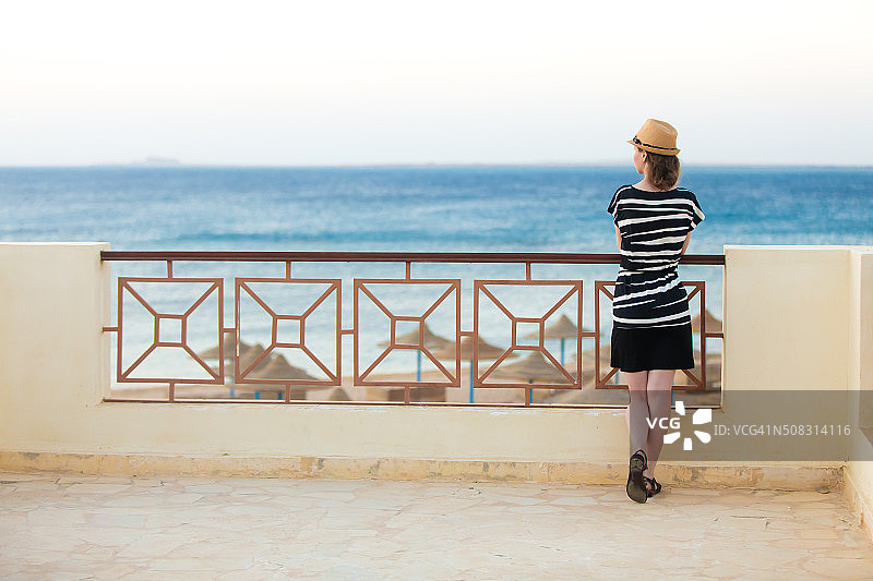 在阳台上欣赏海景的年轻女子图片素材