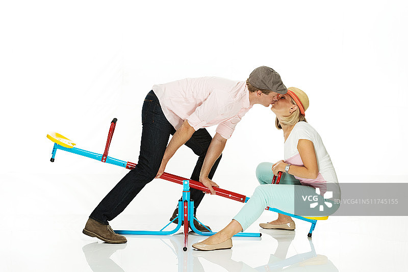 在跷跷板上亲吻的浪漫情侣图片素材