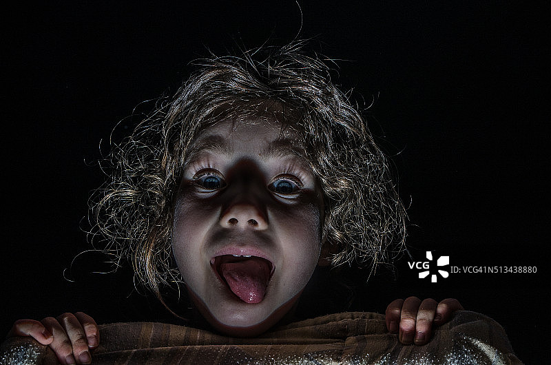 害怕地躲在床单后的小女孩图片素材