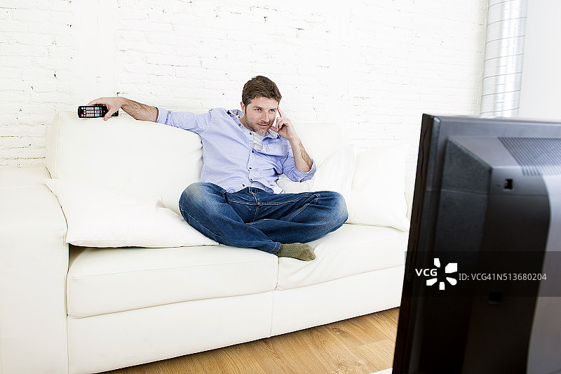 年轻快乐的男人在沙发上看电视放松图片素材