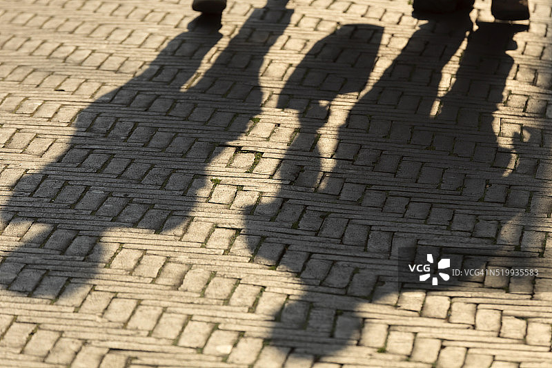 阳光在街上行走的人身上投下阴影图片素材